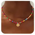 Détail d'un collier de perles colorées avec un pendentif lettre N dorée sur modèle - Lettre N