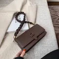 Sac bandoulière en cuir marron foncé avec bandoulière tressée et détails dorés chic - café