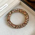 Detailed close-up of golden spiral bracelet with leopard print pattern in jewelry box - Gold Leopard Spiral Bangle