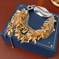 Multilayer chain bracelet with gold leaf charms and silver toggle clasp on a jewelry box - Gold Silver Leaf Tassel Bracelet