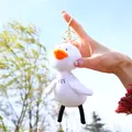 Plush white duck keychain with golden metal ring held against a sunny outdoor background - Gold Buckle - White / 15cm
