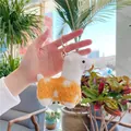Cute orange alpaca plush keychain with white polka dots held in a bright indoor garden - Gold Metal Buckle / Yellow