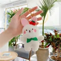 Detalle de un llavero de conejo de peluche con cereza roja y una bufanda verde - Gancho Dorado Conejo Blanco