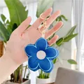 Detail of a dark blue plush fabric flower keychain with gold metal clasp held in hand - Blue - Gold Clasp