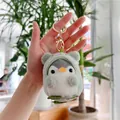 Close-up of cute plush penguin keychain wearing a green frog hoodie held by hand - Gold Clasp / Green / 10cm
