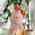 Nahaufnahme des rosa Plüschbär-Anhängers mit blauem Band und silberner Metallkette - Fleischfarbener Hase