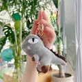 Close-up of a grey plush dinosaur keychain with a gold metal ring held in hand - Gray (Gold Clasp) / 11cm