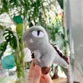Detail shot of a small grey plush dinosaur keychain held in hand against green leaves - Gray (No Chain) / 11cm