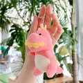 Primo piano del portachiavi a dinosauro di peluche rosa tenuto in mano con trama morbida - Rosa / Catena Pendente