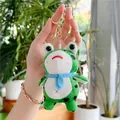 Nahaufnahme vom süßen grünen Frosch-Plüschanhänger mit blauem Schal und Goldclip - Goldener Metallverschluss Stil / Blauer Schal Stil