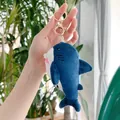Dettaglio del portachiavi peluche a squalo blu con chiusura dorata tenuto in mano - 13cm / Chiusura Dorata / Blu navy