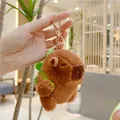 Close-up of cute brown capybara plush toy with a green backpack and golden keychain - Turtle Backpack Style (10cm) / Gold D-Ring Buckle