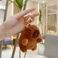Brown capybara plush keychain with gold lobster clasp shown in a cozy indoor setting - Original Style (10cm) / Gold Clasp