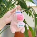 Llavero de peluche de carpincho rosa con gorra de béisbol azul ante unas plantas verdes - Sosteniendo Pelota (Cadena) / Rosa