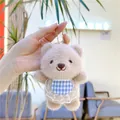Close-up of fluffy plush bear keychain with lace blue bib held in hand for size - Hanging Chain / Khaki