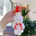 Detail of a plush white Christmas bear keychain with red hat held in hand - Gold Lobster Clasp / Bleached White Red White Scarf
