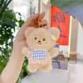 Close-up of plush bear keychain with blue plaid apron and lace trim held by hand - Brown Bear / Plain Chain