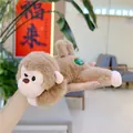 Detailed view of a small brown plush monkey toy with a green label held in a hand - Light Brown Monkey / 20cm