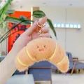 Detailed view of a plush croissant keychain with a cute smiley face and gold clasp - Croissant (Golden Buckle)