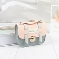 Λεπτομέρεια από μίνι τσάντα χιαστί σε ροζ και γκρι με χρυσό κούμπωμα και ετικέτα 'DELICATE' - Μπλε Καπάκι