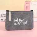 Detail der gestreiften Canvas-Kosmetiktasche mit 'but first, make-up!' Aufdruck und Trageschlaufe - Gestreift Grau