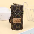 Macro view of vintage leather mini bucket pouch with metal zipper and golden M-pattern - Brown