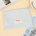 Close-up of mint green fabric cosmetic bag with blue ring zipper and text patch detail - Horizontal / Mint Green (Horizontal)