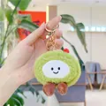 Detailed close-up of a green plush avocado keychain with golden metal clasp held in hand - Gold Clasp / Green