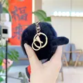 Close-up of a fluffy black plush ball keychain with a sturdy gold metal ring fastener - Billiards Style (Gold Buckle)