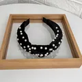 Elegant black velvet knotted headband with white faux pearls on a wooden display tray - Black