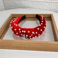 Red velvet knotted headband with white pearls on a mirror tray background - Red