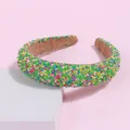 Detailed view of colorful sprinkle-decorated sponge headband on a minimalist display stand - Green