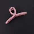 Sleek pink glossy hair claw clip in a minimalist crossover design on black background - Pink Twist Style