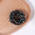Primer plano de coletero de punto colorido con pompones sobre bandeja de madera - Negro