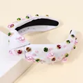 White knotted fabric headband with pink pearls and multicolored rhinestones on display - White