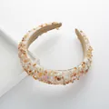 Detailed shot of padded headband with beige stones, white pearls, and soft velvet lining - Champagne