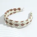 Cerchietto retrò in maglia a scacchi marrone e beige su un supporto decorativo bianco - Cachi