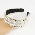 Close-up of woven headband featuring gold pyramid studs and clear rhinestones on beige fabric - Beige