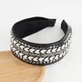Detail of wide padded headband with studs, woven patterns, and sparkling rhinestones - Black