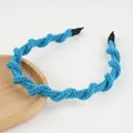 Détail d'un bandeau en maille bleue avec fils pailletés sur un plateau en bois - Vague Bleue