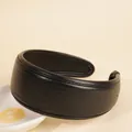 Detail eines schwarzen PU-Leder-Stirnbands mit feiner Naht auf beigem Hintergrund - Schwarz