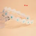 White lace headband with embroidered blue daisies on a minimalist light orange background - Blue