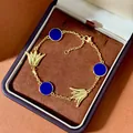 Goldenes Blumenarmband mit blauen Steinen und Tulpenanhängern in einer Schmuckschatulle - Messing Echtvergoldet/Synthetischer Lapislazuli / Goldblau