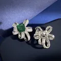 Makro-Detail von silbernen Schleifenohrringen mit grünem Smaragdschliff und Zirkonia - Ohrstecker / Silberne Ohrstecker
