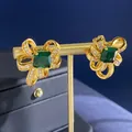 Ohrstecker mit smaragdgrünen Zirkonia-Schleifen in Goldoptik und glänzenden Akzenten - Ohrstecker / Goldene Ohrringe