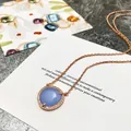 Vue rapprochée d'un collier en or rose avec un pendentif en pierre bleue taillée en poire - Or Rose et Bleu Ciel