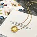 Détail d'un collier doré avec cristal jaune en forme de poire et sertissage micro-pavé - Or + Jaune