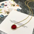 Détail macro du pendentif coeur en cristal rouge sur chaîne dorée avec halo de zircon - Or+Rouge