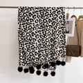 Détail d'une écharpe léopard d'hiver avec pompons noirs et tissu doux et épais - 180x68cm / Noir & Blanc
