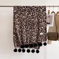 Close-up of leopard print cashmere feel scarf with decorative black pom-pom tassels - 180x68cm / Brown